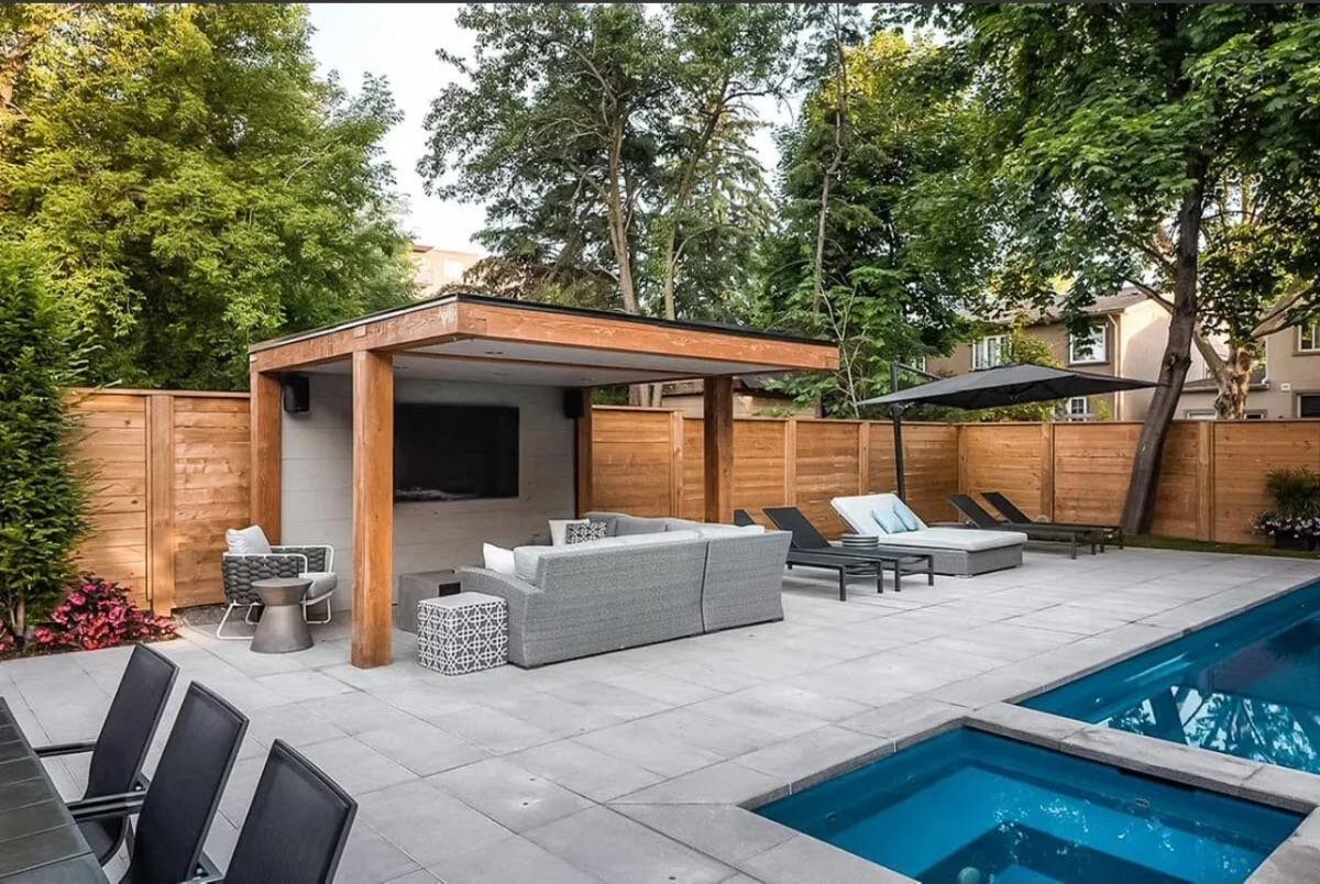 Modern wood pool cabana with a TV and sectional beside a pool and spa