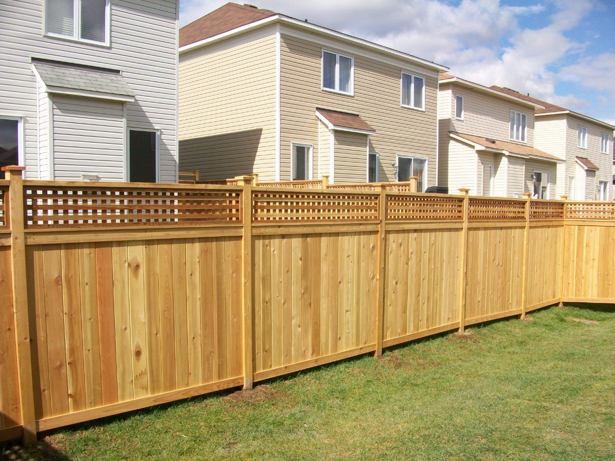 Cedar board privacy fence with a lattice top along a suburban backyard