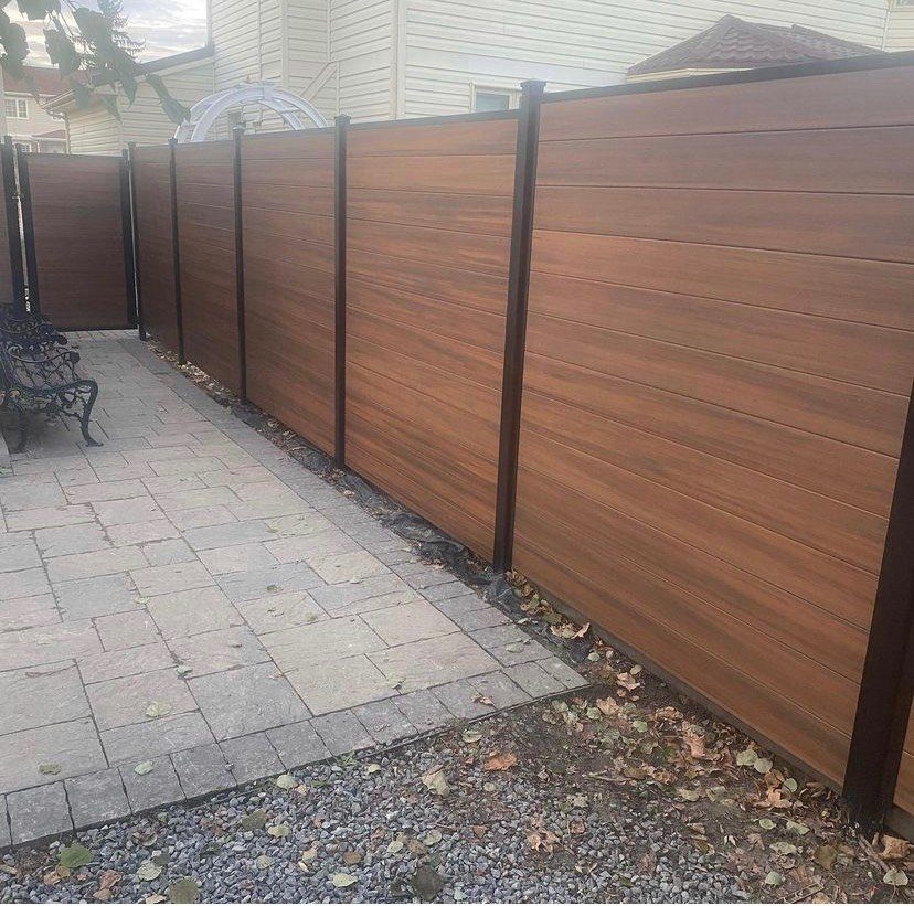 Mocha horizontal composite privacy fence with black posts along an interlock patio