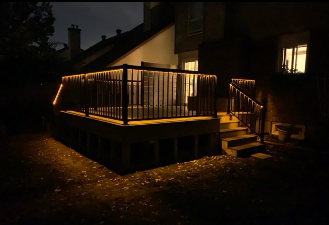Raised deck at night with warm strip lighting under the top rail and along the stairs