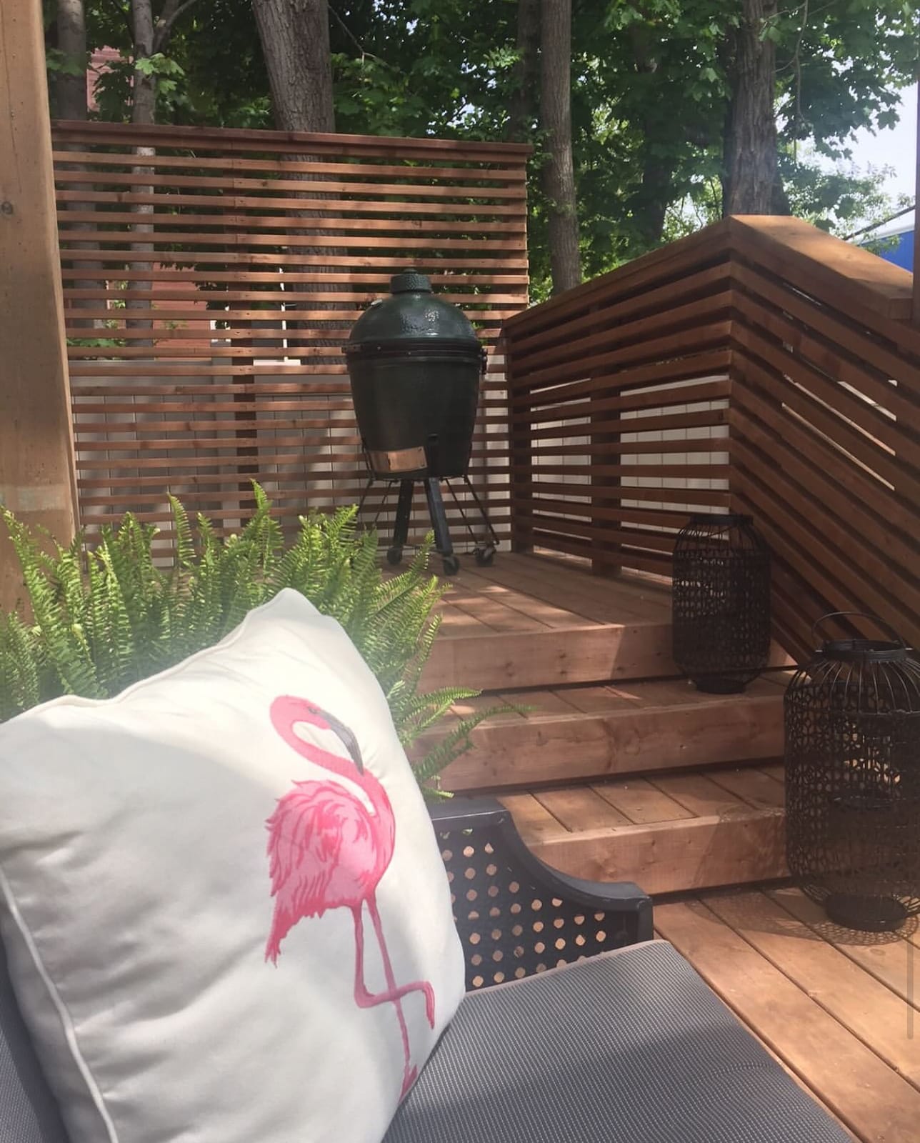Wood deck with horizontal slat privacy screens and steps, with a grill in the corner