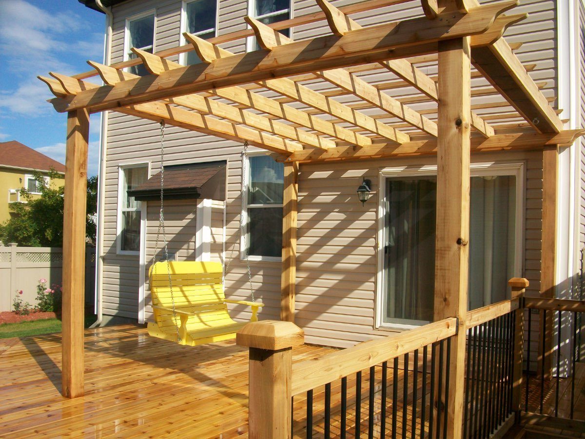 Cedar pergola over a new deck with a yellow porch swing and black railing