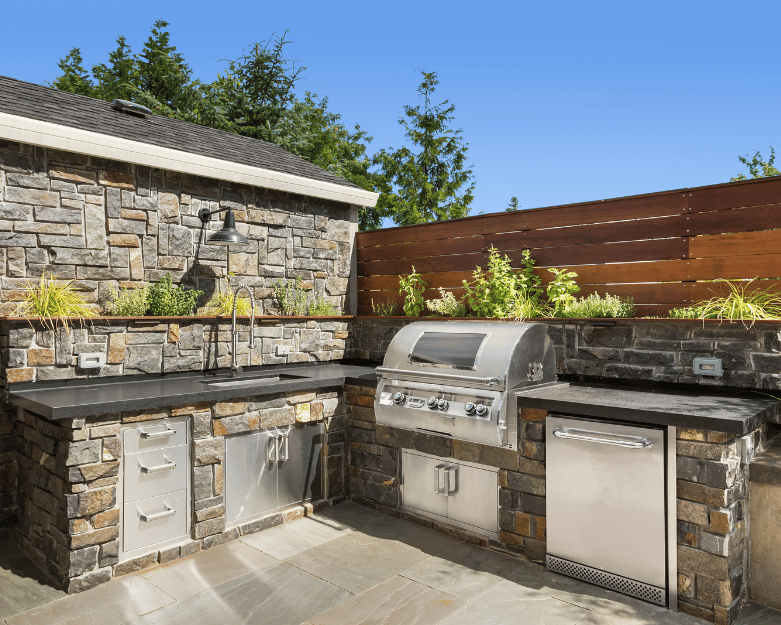 Modern outdoor kitchen with built-in grill, stone countertops, and seating area in Ottawa backyard